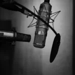 WELL SAID: TORONTO SPEECH THERAPY. A black and white photo of two microphones and a pop filter set up in a recording studio for adults with ADHD, with a blurred background.